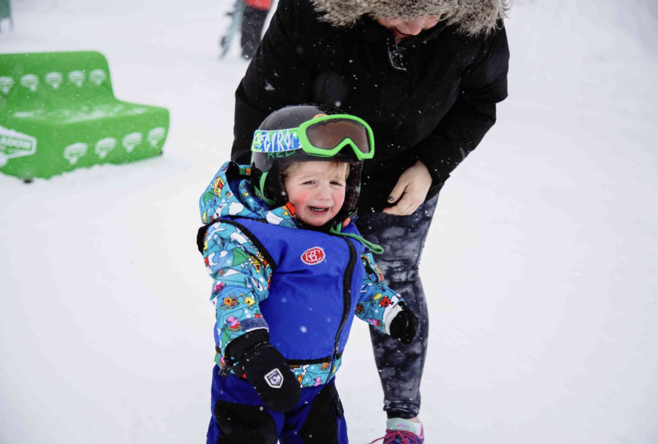 An adult caring for a young child on snow