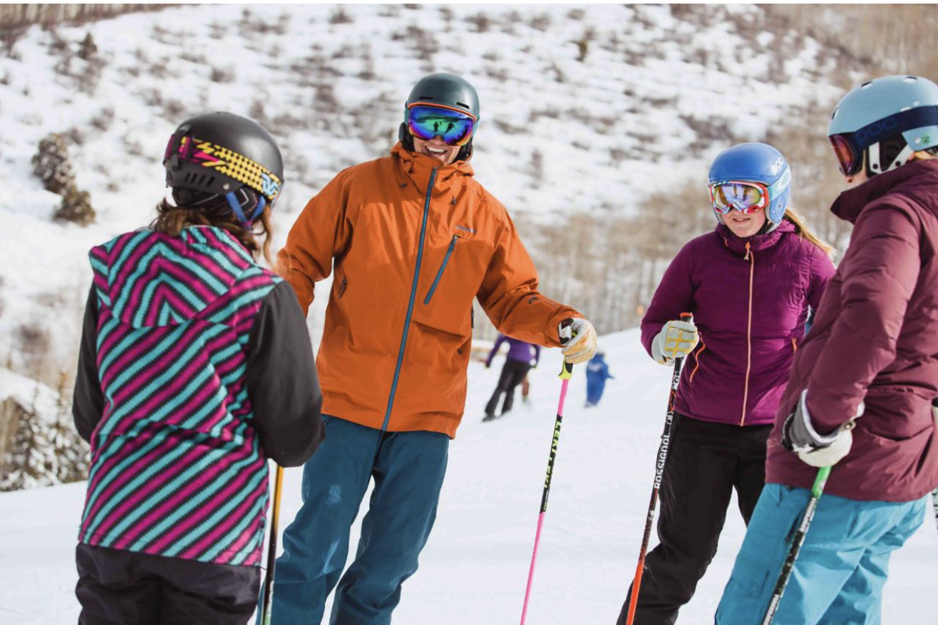 An instructor talking with older children at a ski resort